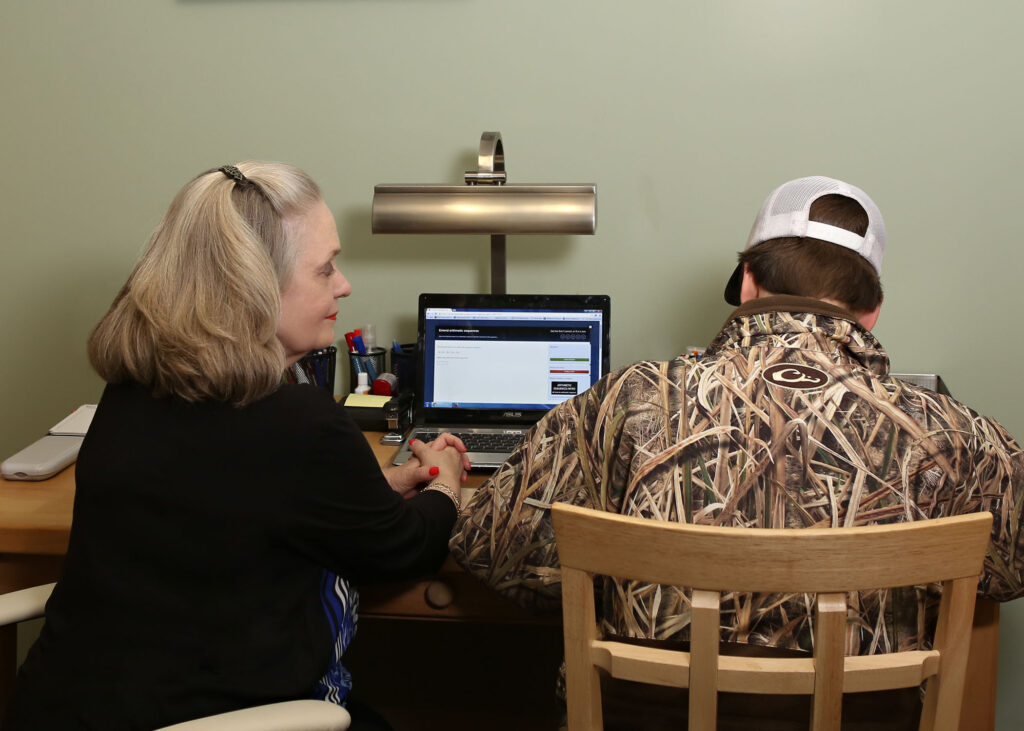 Two people sitting at a table with a laptop.